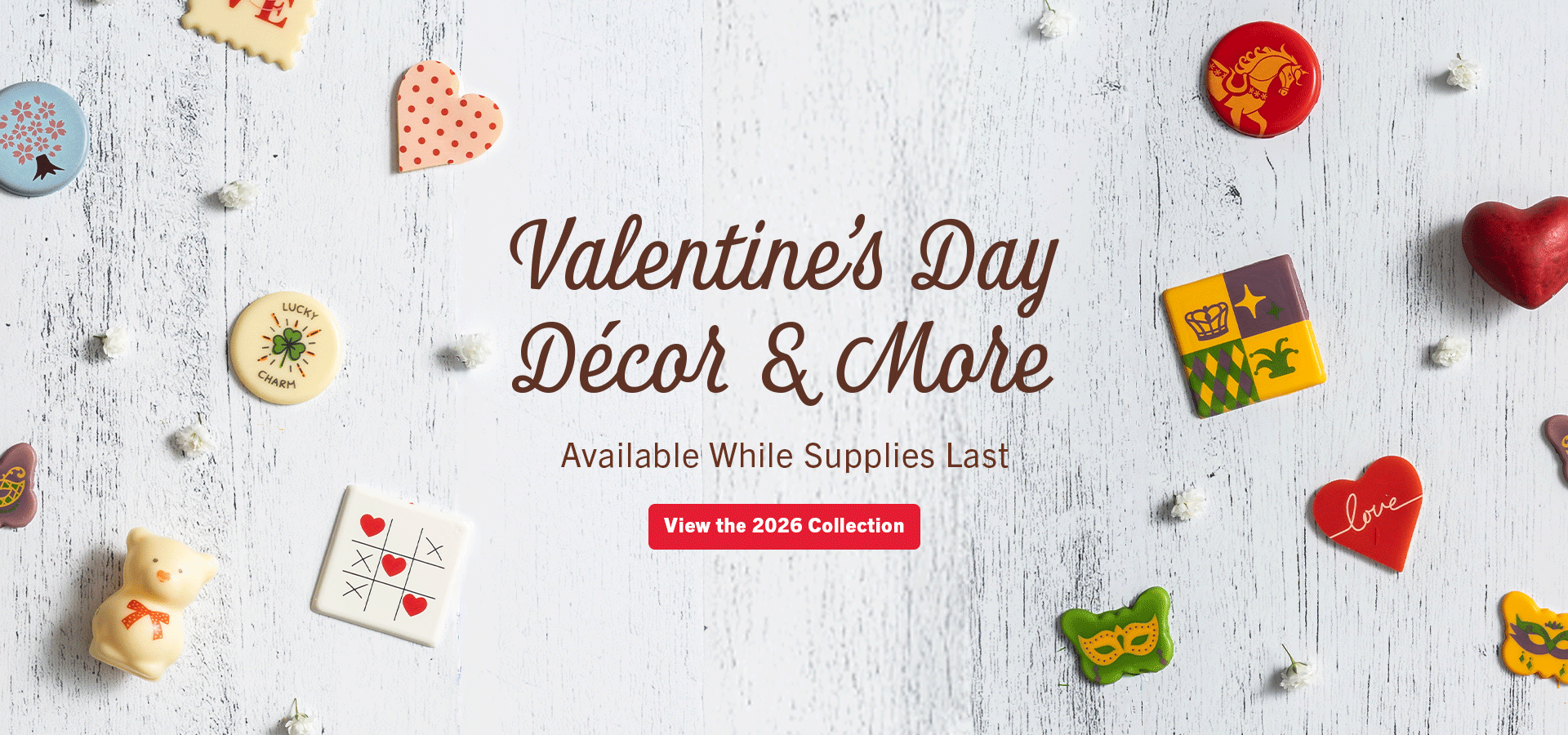 Valentine's Day chocolate décor plaques arranged on whitewashed wood.